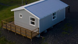 Ein kleines, eingeschossiges Gebäude mit einem Metalldach und einer Holzterrasse.