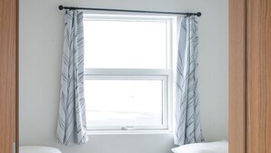 Ein Schlafzimmer mit zwei Betten, einem kleinen Nachttisch und einem Fenster mit Vorhängen.