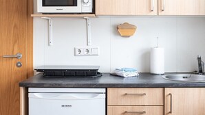 Eine kompakte Küche mit Mikrowelle, Kaffeemaschine und kleinem Kühlschrank.