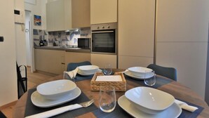 A modern dining area with a wooden table set for four, including plates, bowls, glasses, and cutlery. A microwave and oven are visible in the background. - NoLo Flat by Interhome (Milan)