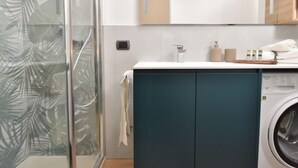 A modern bathroom with a glass shower enclosure, a built-in washing machine, and a vanity with a mirror. - NoLo Flat by Interhome (Milan)