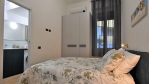 A bedroom with a bed, a wardrobe, a bathroom, and a window with curtains. - NoLo Flat by Interhome (Milan)