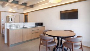 A modern kitchen with a central island, a dining table with chairs, a flat-screen TV mounted on the wall, and pendant lighting. - Villa Divina22 - APT Prima with pool and lake view (Veneto)
