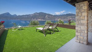 A patio with two lawn chairs and a small table, overlooking a lake and mountains. - Villa Divina22 - APT Prima with pool and lake view (Veneto)
