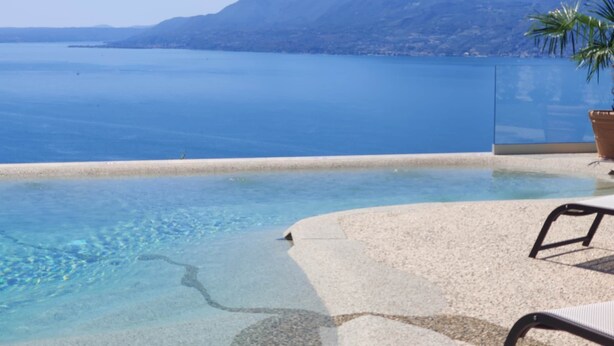 A clear blue pool with a mountain view, a palm tree, and a chair. - Villa Divina22 - APT Prima with pool and lake view (Veneto)
