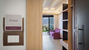 A hotel room with a view of mountains, a purple sofa, and a wooden bookshelf. - Villa Divina22 - APT Prima with pool and lake view (Veneto)