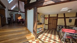 Une cuisine spacieuse avec un carrelage à motifs, des poutres apparentes et un escalier menant à un niveau supérieur.