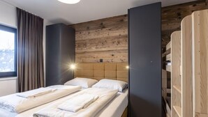 Una habitación de hotel moderna con un panel de madera, una cama grande con ropa blanca impecable y un armario empotrado con acabado de madera.