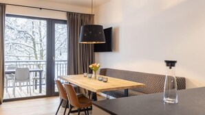 Un'area pranzo moderna con un tavolo in legno, sedie e una lampada a sospensione nera.