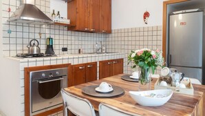 A kitchen with wooden cabinets, a stainless steel stove, and a refrigerator. - Neapolitan Style Apartment (Napoli)