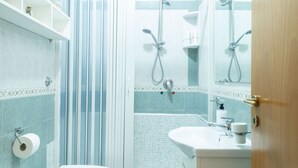 A bathroom with a shower, toilet, sink, and shelves with toiletries. - Neapolitan Style Apartment (Napoli)