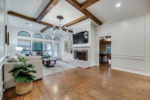 A spacious living room with a fireplace, a large TV, and a pool table.
