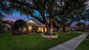 A residential house with a well-maintained lawn, a large tree in the front yard, and a sidewalk leading to the entrance. - 4 Bedroom3 Bath,Pool table, Pool, Crib (Plano)