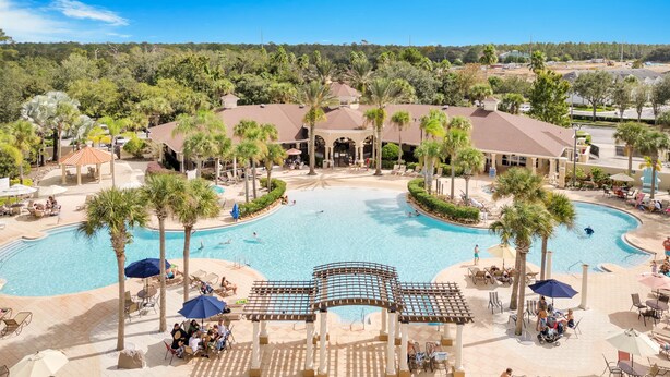Um resort com piscina central, palmeiras e áreas de estar ao ar livre.