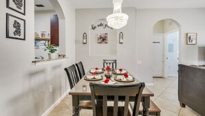 Uma sala de jantar com lustre, obras de arte emolduradas e um letreiro na parede com a frase 'sejam nossos convidados'.