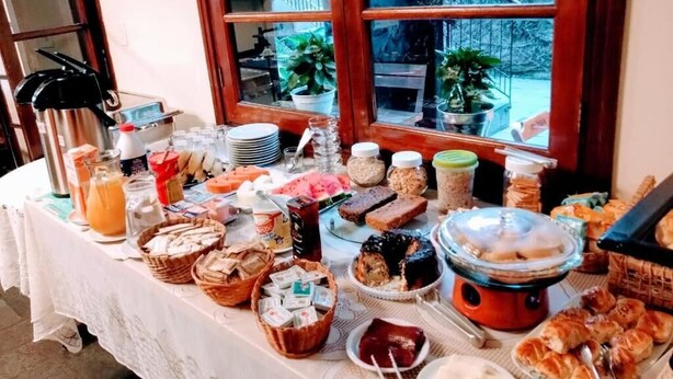 Una mesa de buffet con diversos alimentos y bebidas, frente a una ventana que da a vistas de vegetación.