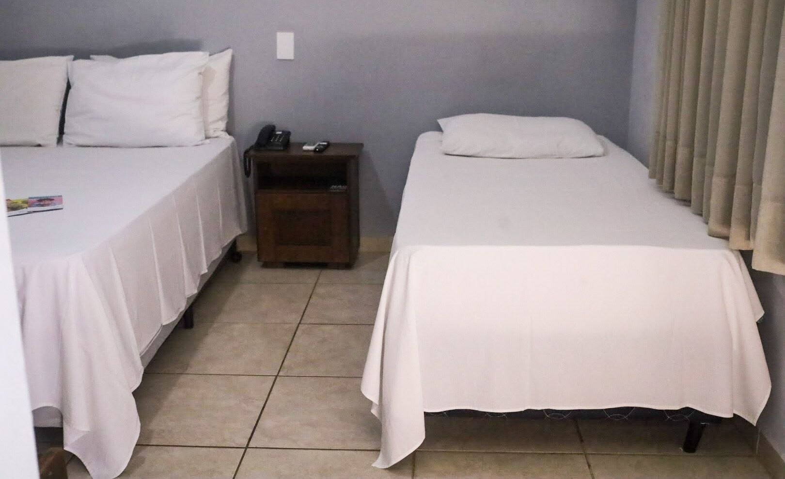 A room with two beds, a nightstand, and a wall socket.