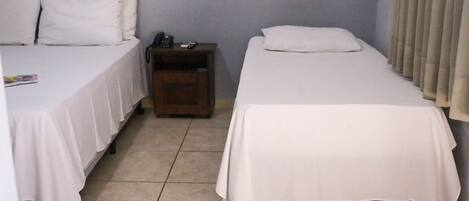A room with two beds, a nightstand, and a wall socket.