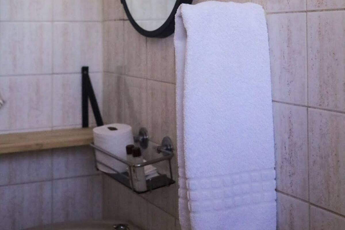 Une salle de bain équipée d’un lavabo, d’un miroir, d’un porte-serviettes et d’un support à papier toilette.