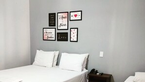 Habitación de hotel con una cama, dos mesitas de noche y una pared con citas inspiradoras enmarcadas.