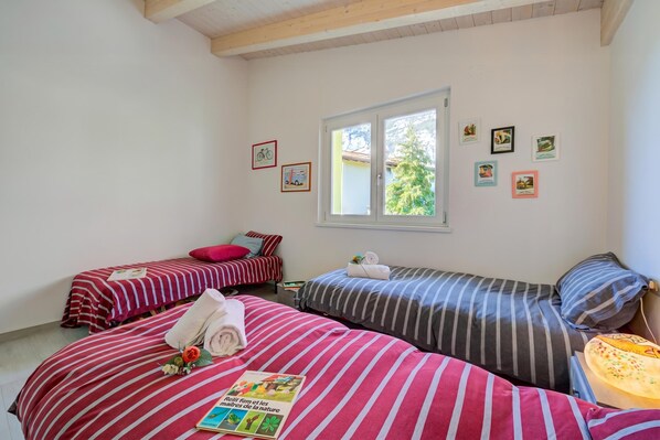 Une chambre avec deux lits, une fenêtre et plusieurs tableaux encadrés accrochés au mur.