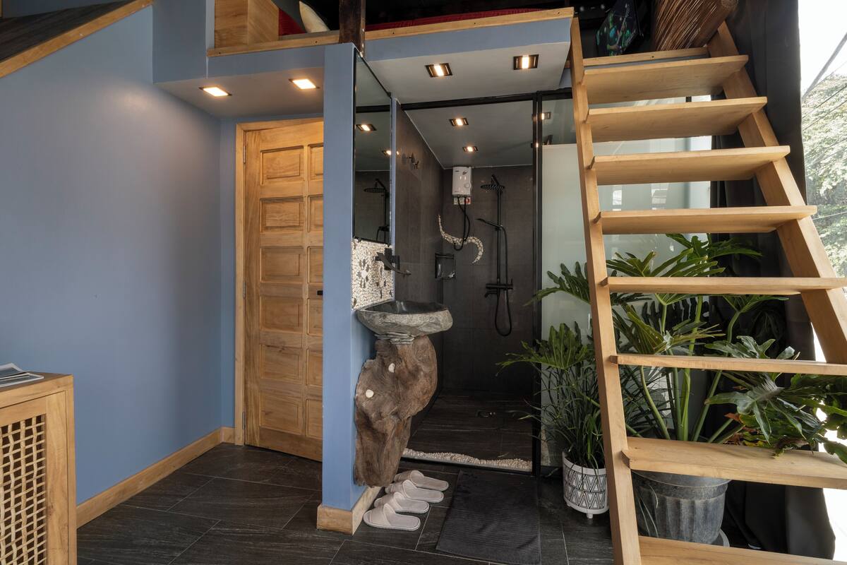 A modern interior with a wooden staircase, a stone sink, and a shower area.