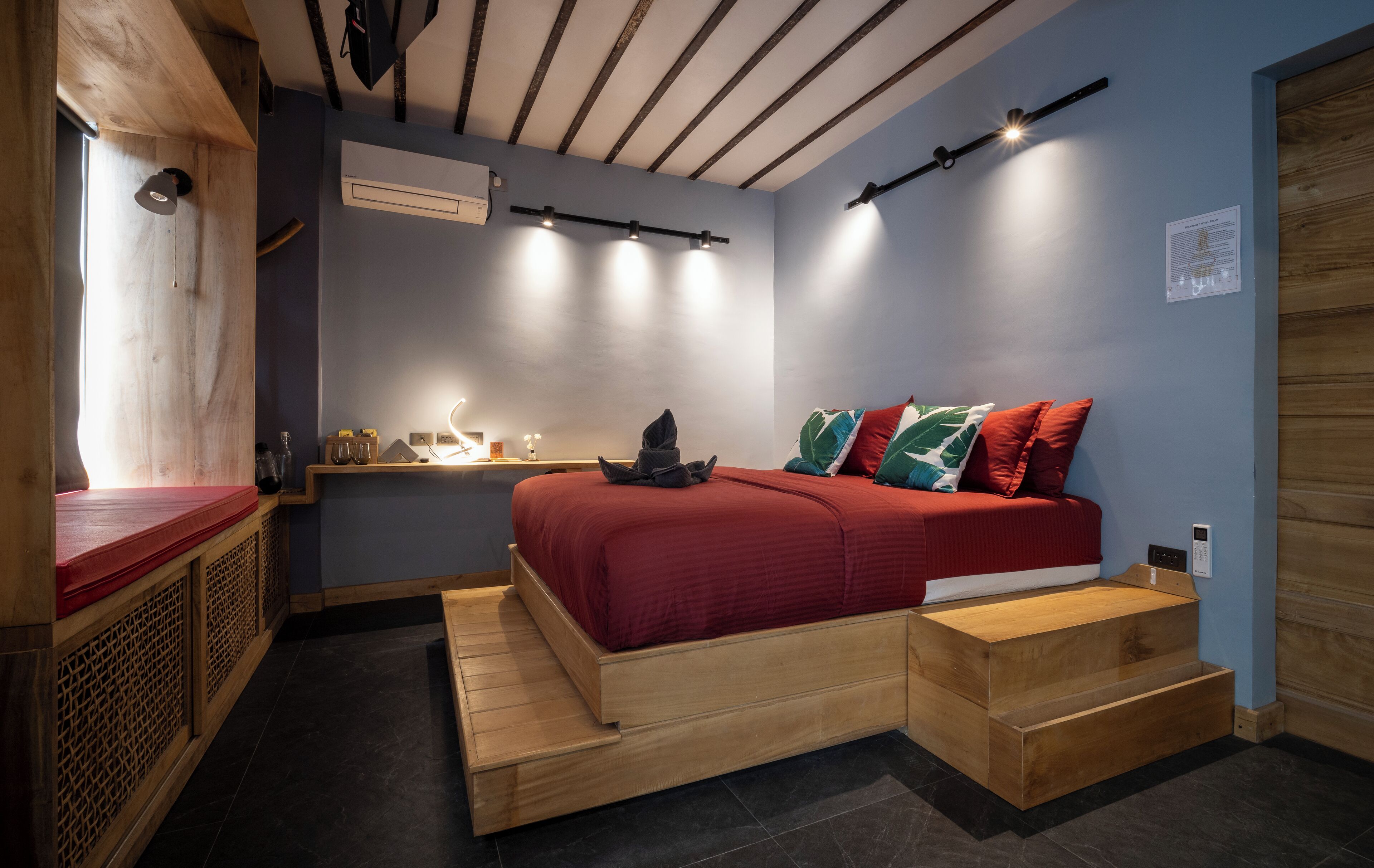 Un dormitorio con cama, escritorio y silla. Hay una ventana y una puerta.