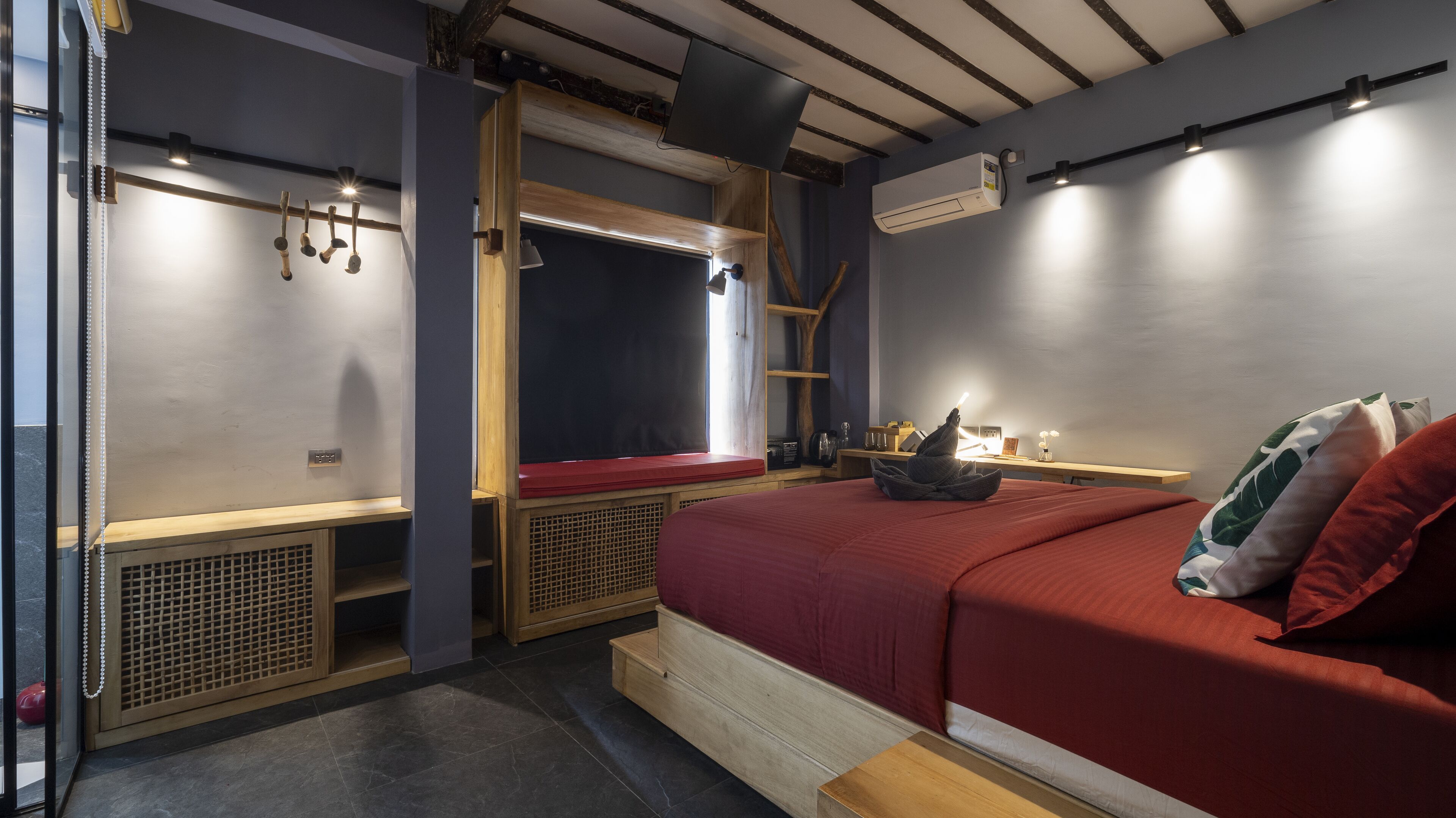 Habitación pequeña con cama, ventana, estante y una mesita de noche con lámpara.