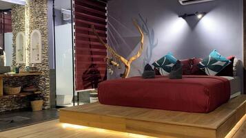Un dormitorio moderno con una cama roja, una pared de piedra y un techo de madera.