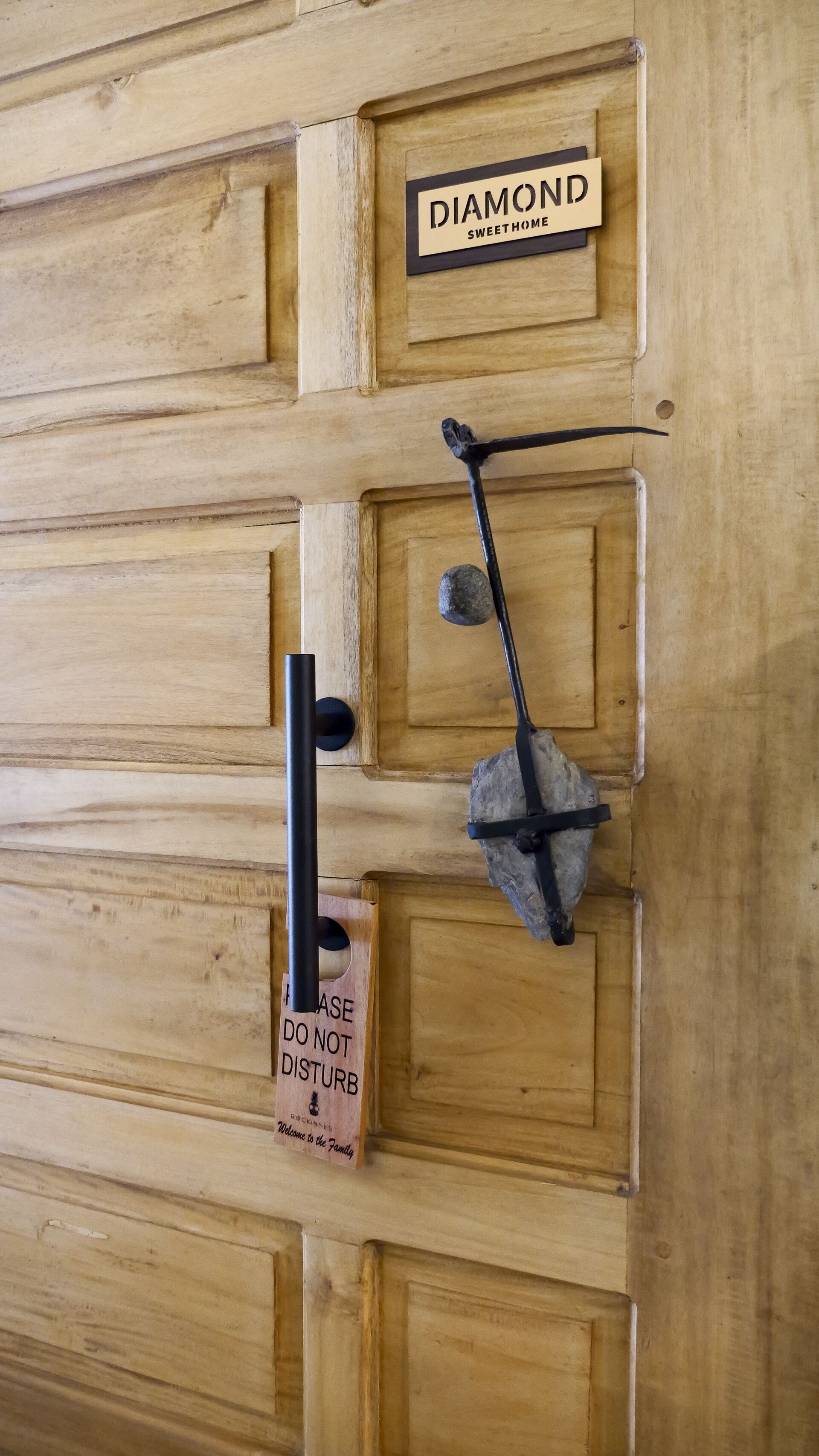 A wooden door with a sign that reads "DIAMOND SWEET HOME" and a sign below it that says "PLEASE DO NOT DISTURB Welcome to the Family."