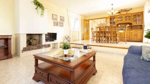 Ein Wohnzimmer mit Kamin, ein Essbereich mit Holzmöbeln und eine Küche mit Holzausstattung.