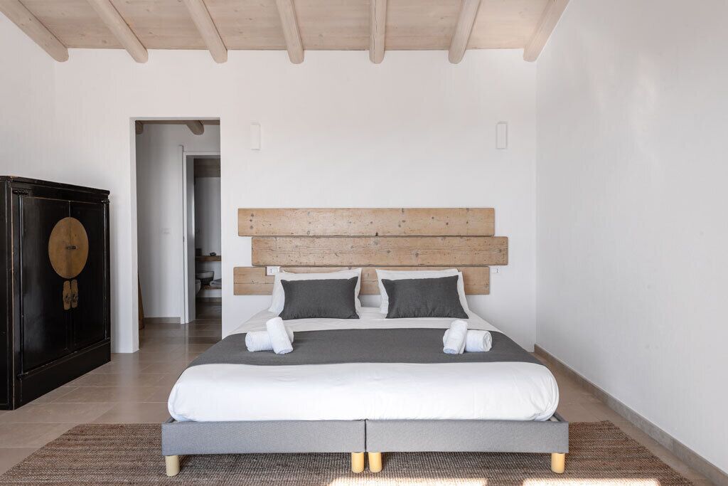 Un dormitorio moderno con una cama grande, cabecera de madera y un armario oscuro.