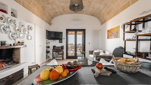 Una cuina àmplia amb sostre de pedra, zona de menjador amb taula preparada per a dinar, i saló amb sofà i televisió.