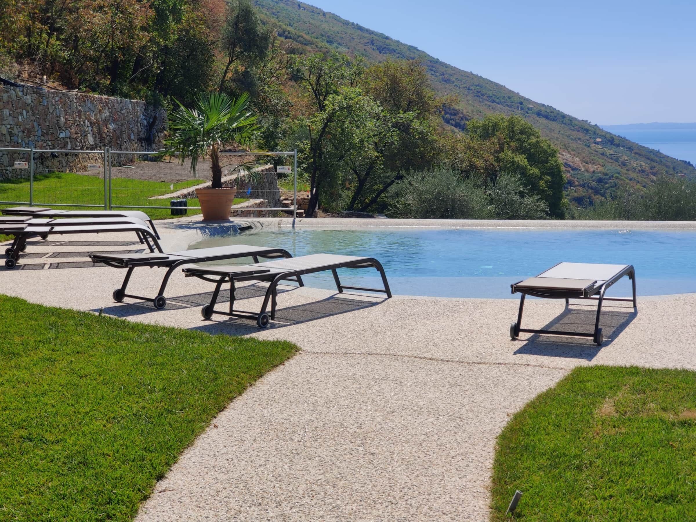 A pool area with lounge chairs and a stone wall.