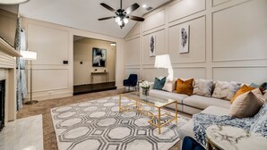 A modern living room with a sofa, coffee table, and a ceiling fan. - Updated 4 Bedroom Home Pool, Sleeps 8 Wifi Garage (Carrollton)