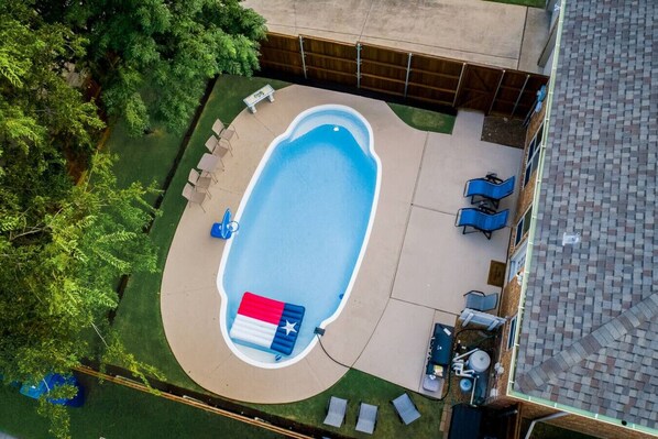 Vista aerea di un giardino sul retro con piscina, circondato da un pontile in legno e da una zona verde.