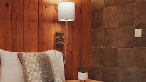 Een slaapkamer met een houten hoofdbord, een bedlampje, een kleine plant en een zachte deken.