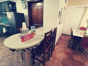 A kitchen with a dining table, chairs, and a refrigerator.