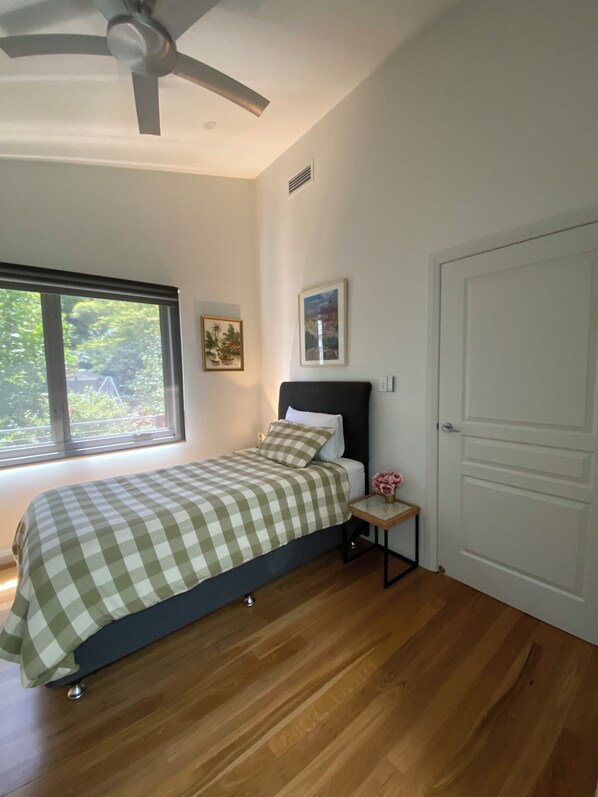 Un dormitorio con cama, ventilador de techo, ventana y puerta.