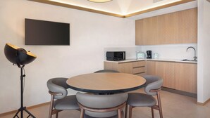 A modern kitchen with a round dining table and four chairs, a black-framed pendant light, a microwave, a coffee maker, and a sink. - Villa Divina22-APT Unica-With pool and lake view (Veneto)