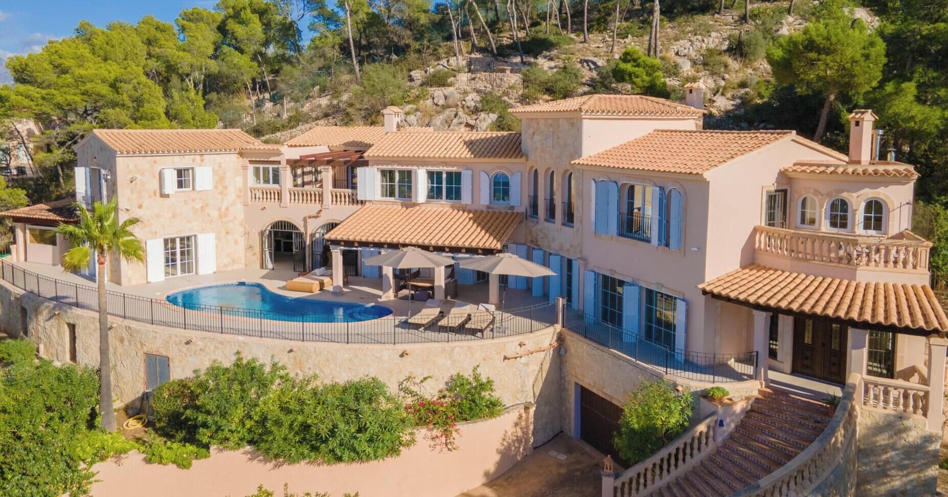 Une villa de style méditerranéen dotée d’une piscine, d’un jardin aménagé en terrasses et offrant une vue sur les collines environnantes.