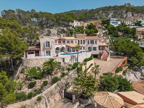 Eine Villa an einem Hang mit Swimmingpool, mehreren Balkonen und Blick auf die umliegende Landschaft.