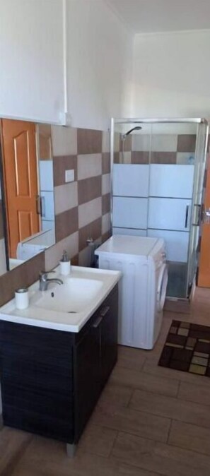 A compact bathroom with a sink, mirror, and a shower area. - Paisible 9 Chambres à Coucher Stationnement Gratuit Pour les Vacances (Flic en Flac)