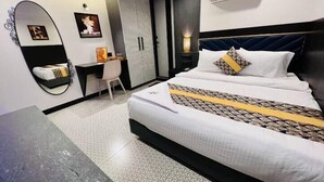 A hotel room with a bed, a desk, a wardrobe, and a mirror. - Rich Hotel (Mumbai)