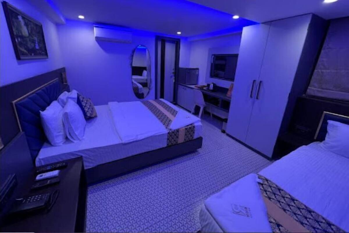 A modern hotel room with a large bed, a desk, and a wardrobe.