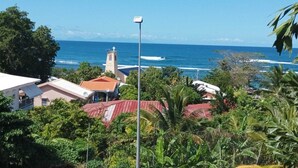 Vista costera con una iglesia, abundante vegetación y cielo azul despejado.