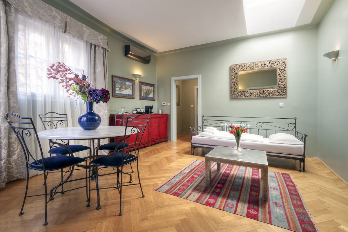 A well-lit room with a dining table, chairs, a bed, and a red cabinet.