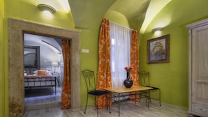 A room with a bed, a table with chairs, a vase with flowers, and a painting on the wall. - Black Star Suites (Prague)