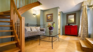 A living room with a wooden staircase, a sofa, a glass coffee table, a red cabinet, and a mirror. - Black Star Suites (Prague)