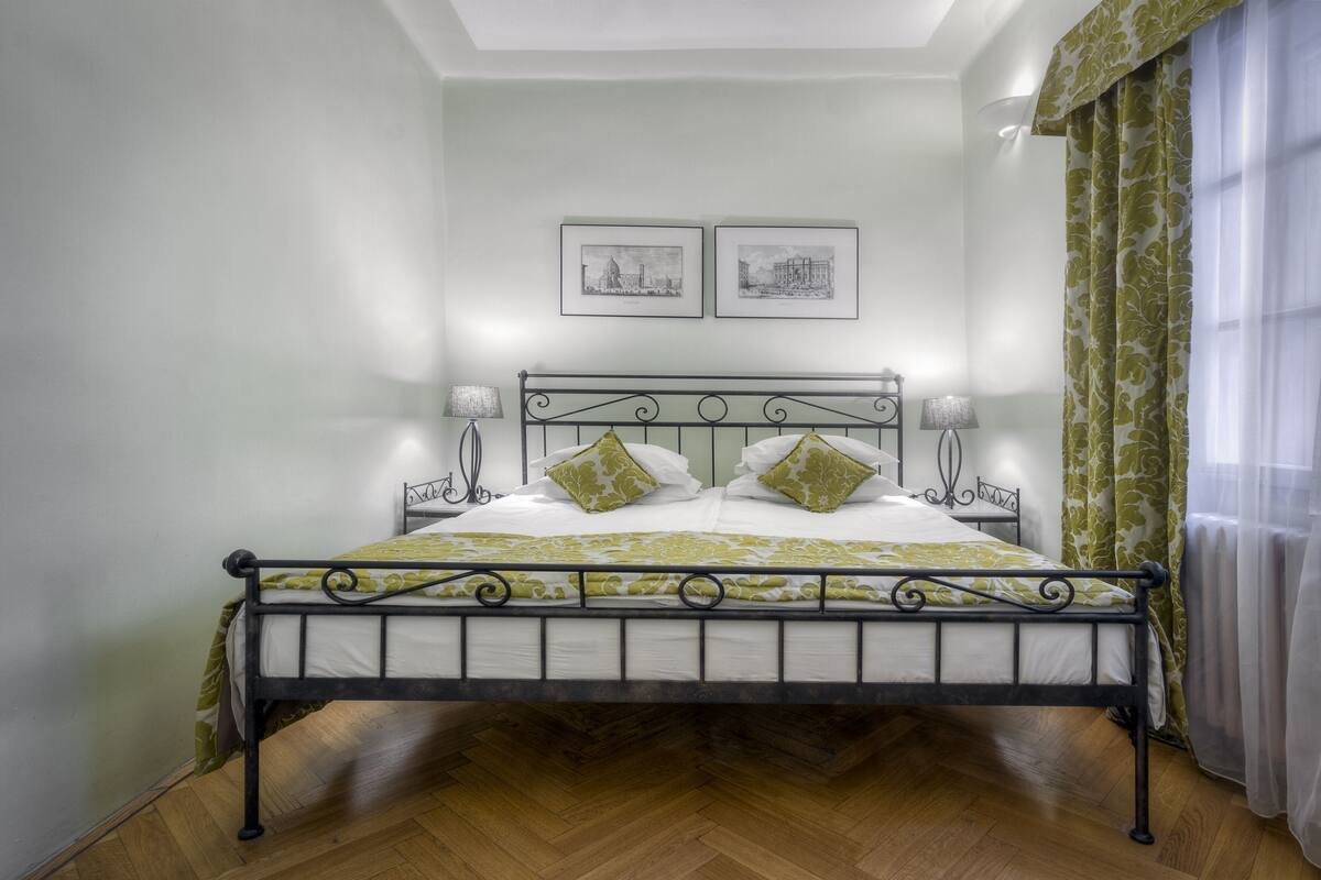 A bed with a metal frame, two pillows, and a green and white bedspread.